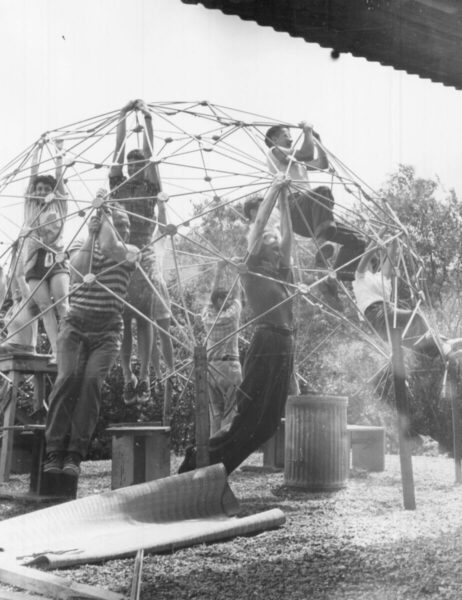 Am Black Mountain College - Relation Magazin Kinder spielen an einem Geodätischen Dom aus Holz und Metall im Freien, umgeben von Bäumen und einem schattigen Dach.