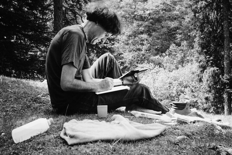 Ein Mann sitzt im Gras und liest